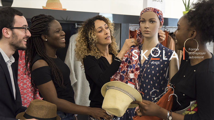 5 vendeurs dans un magasin de vêtement qui assiste à une démonstration de nouage de foulard sur un manequin